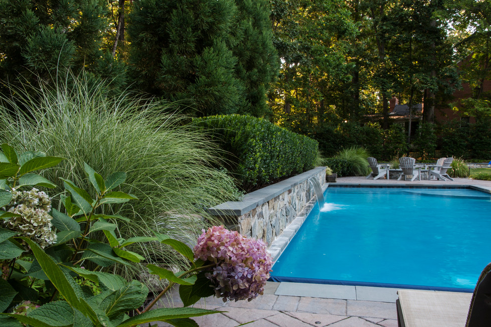 Foto de piscina con fuente alargada ecléctica de tamaño medio rectangular en patio trasero con adoquines de hormigón