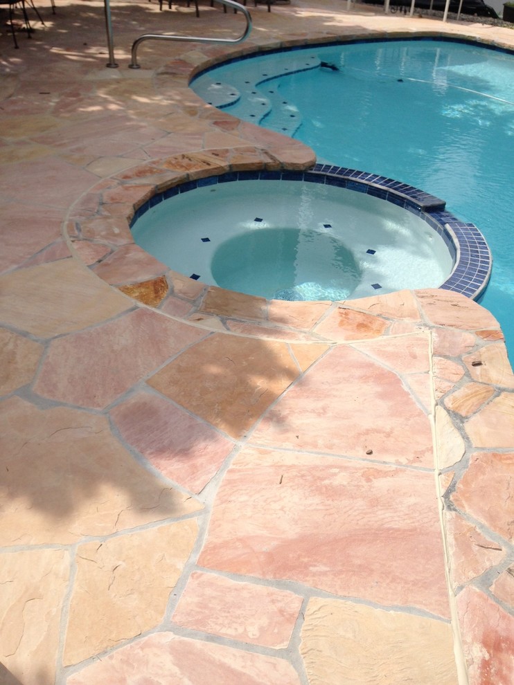 Esempio di una piscina personalizzata dietro casa con pavimentazioni in pietra naturale