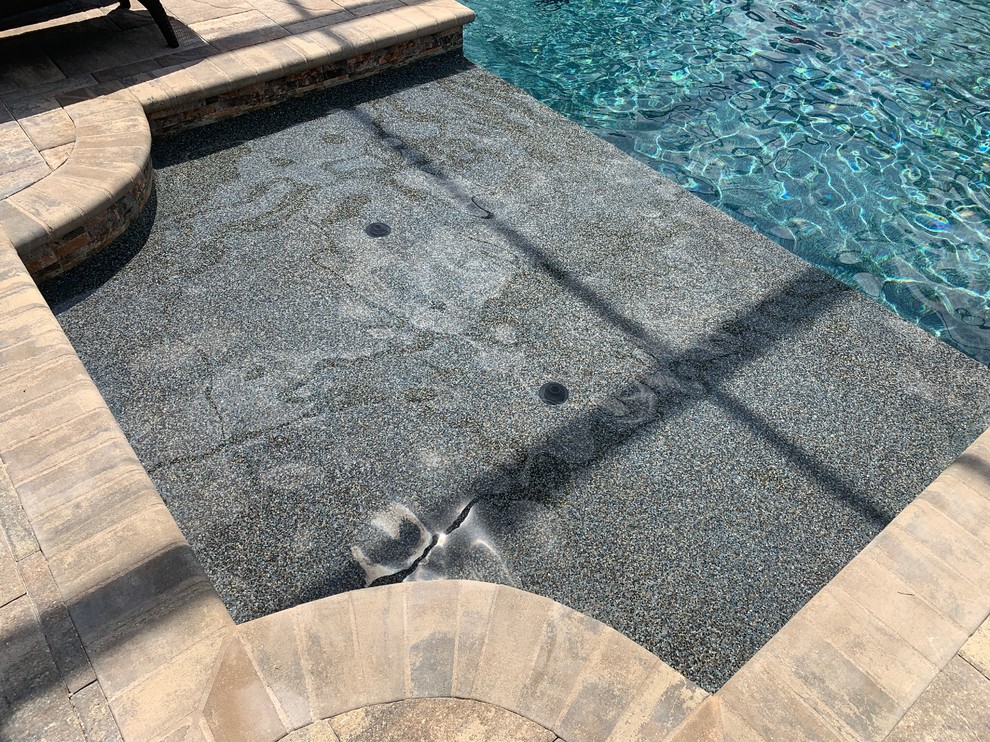 Imagen de piscina de tamaño medio con adoquines de piedra natural
