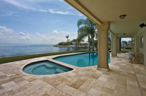 Diseño de piscina alargada tradicional de tamaño medio redondeada en patio trasero con adoquines de piedra natural