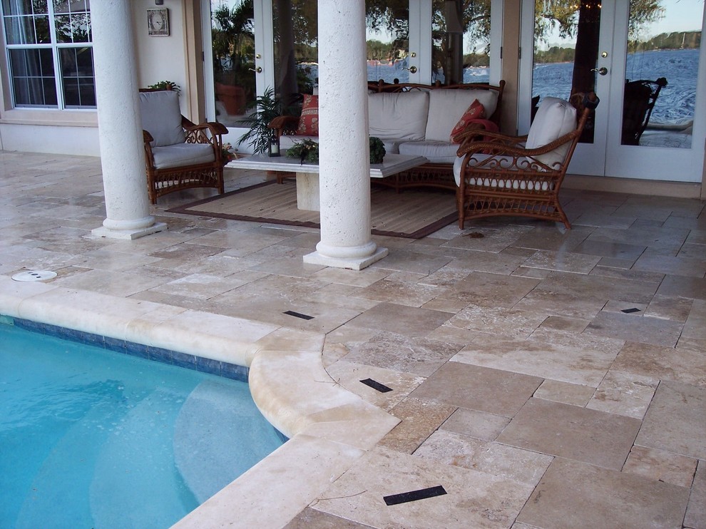 Diseño de piscina alargada tradicional de tamaño medio en patio trasero con adoquines de piedra natural