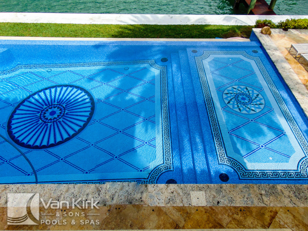 Design ideas for a large classic back custom shaped infinity swimming pool in Miami with a water feature and natural stone paving.