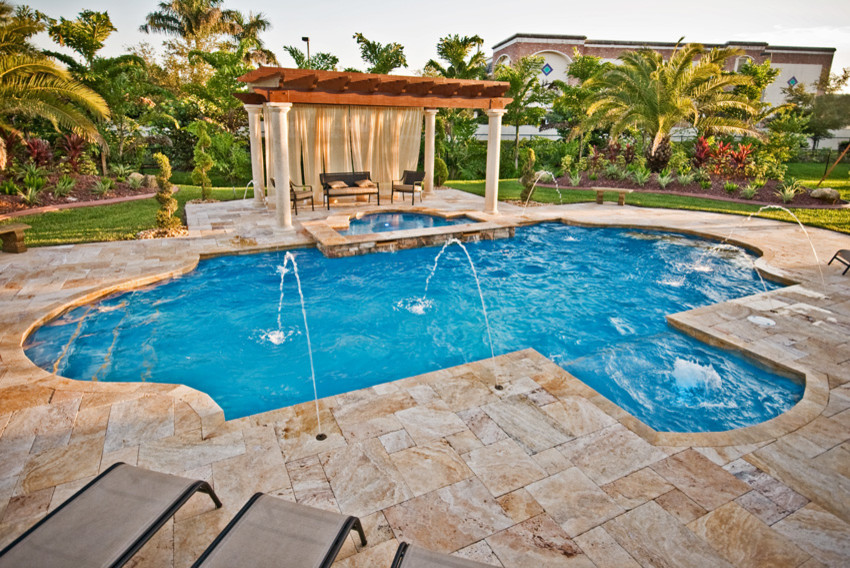 Modelo de piscinas y jacuzzis tropicales grandes a medida en patio trasero con adoquines de piedra natural