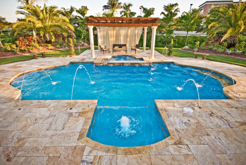 Esempio di una grande piscina tropicale personalizzata dietro casa con una vasca idromassaggio e pavimentazioni in pietra naturale