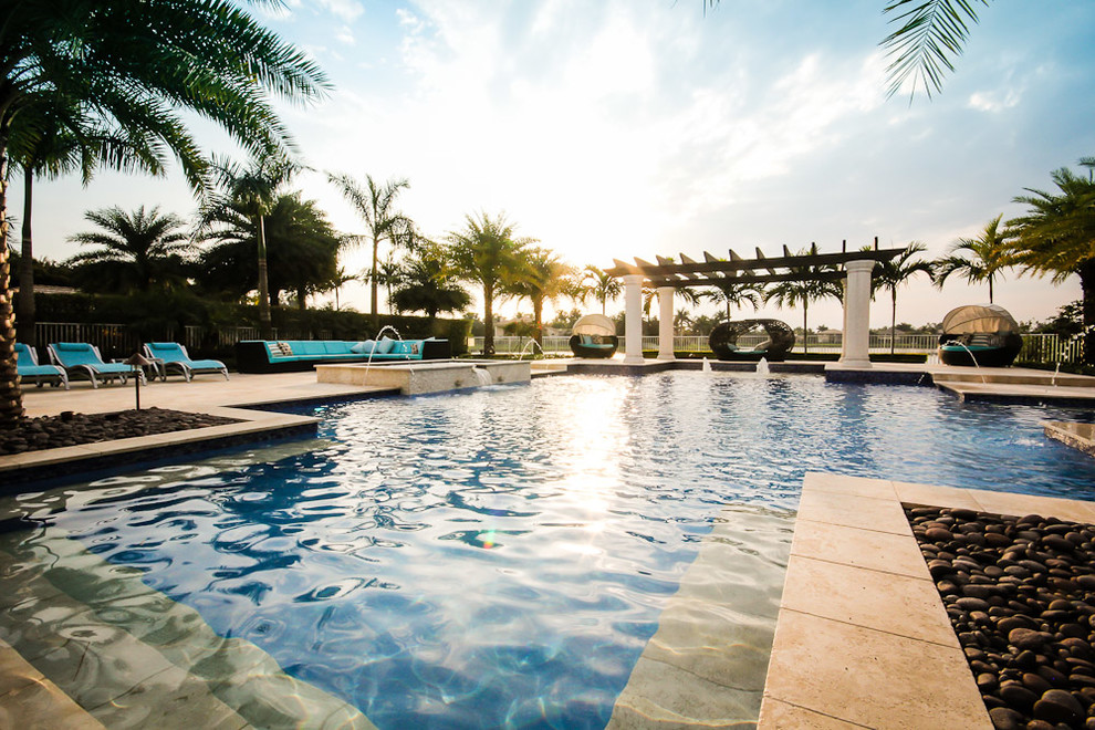 Ejemplo de piscinas y jacuzzis mediterráneos grandes a medida en patio trasero con adoquines de piedra natural