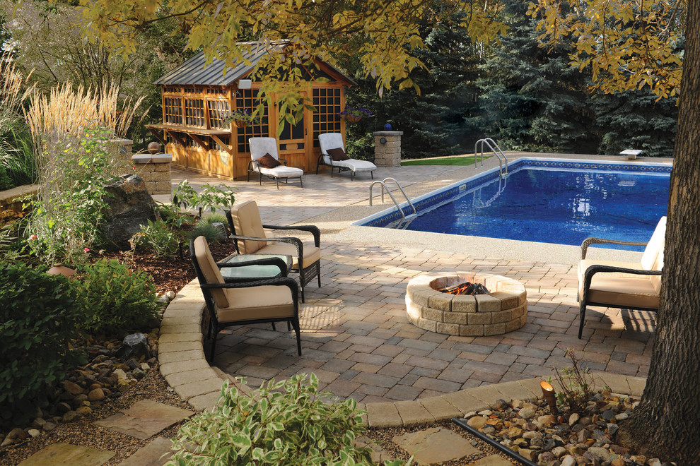 Foto de piscina tradicional de tamaño medio rectangular en patio trasero con adoquines de hormigón