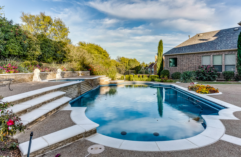 На фото: большой спортивный бассейн произвольной формы на заднем дворе в классическом стиле с фонтаном и покрытием из бетонных плит с