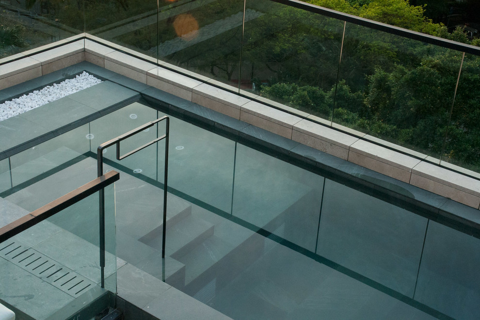 Esempio di una piscina a sfioro infinito moderna rettangolare di medie dimensioni e sul tetto con una dépendance a bordo piscina e pavimentazioni in pietra naturale