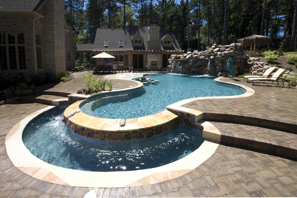 Diseño de piscinas y jacuzzis exóticos de tamaño medio a medida en patio trasero con adoquines de hormigón