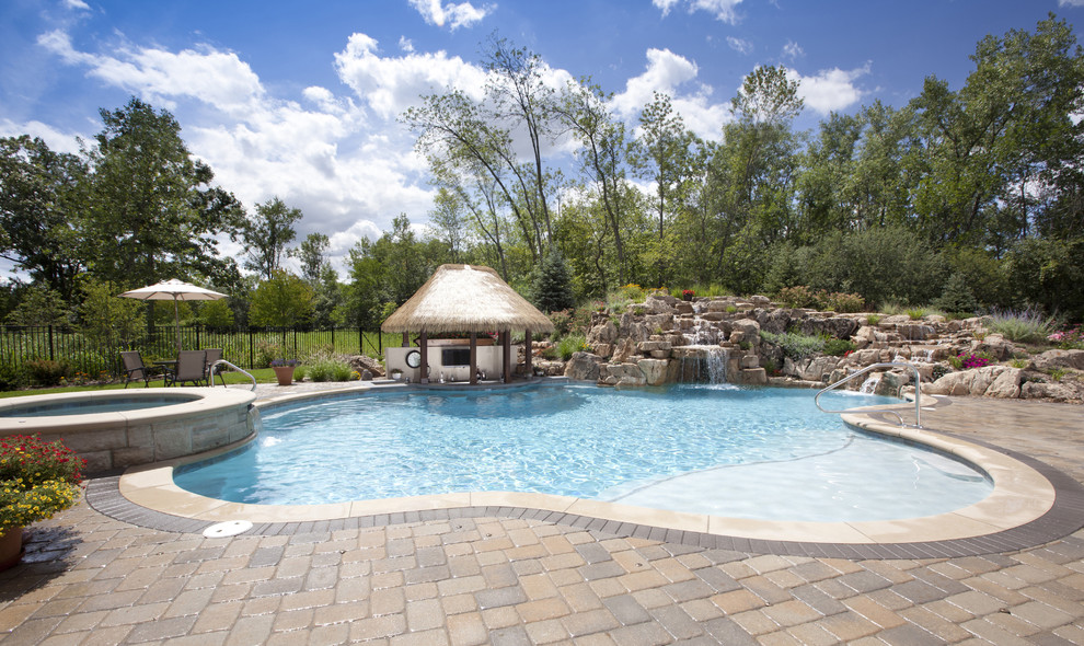 Immagine di una piscina tropicale personalizzata di medie dimensioni e dietro casa con una vasca idromassaggio e pavimentazioni in cemento