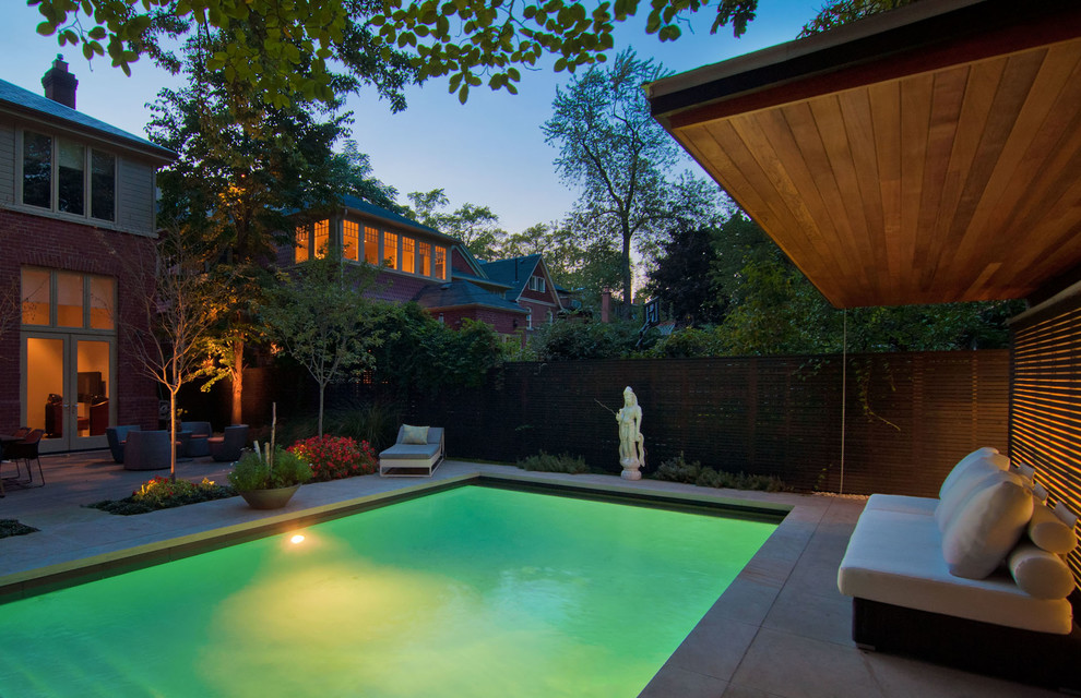 Imagen de piscina alargada moderna de tamaño medio rectangular en patio trasero con adoquines de piedra natural
