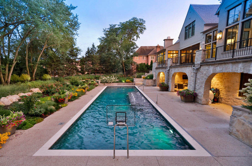 Imagen de piscinas y jacuzzis alargados tradicionales de tamaño medio rectangulares en patio trasero con losas de hormigón