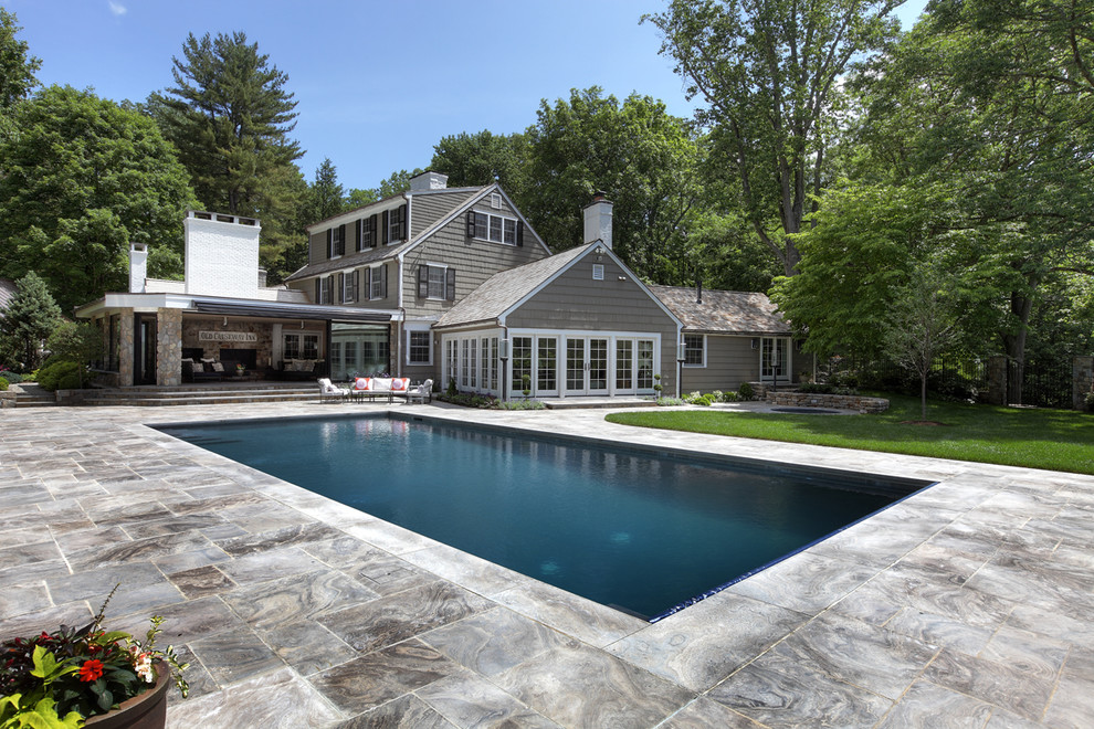This is an example of a large traditional rectangular natural swimming pool in New York with natural stone paving.