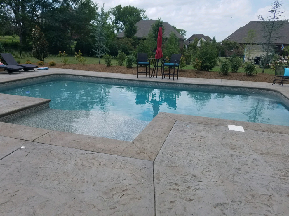 Imagen de piscina alargada clásica de tamaño medio rectangular en patio trasero con suelo de hormigón estampado