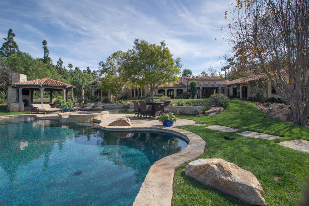 Hot tub - huge mediterranean backyard stone and custom-shaped infinity hot tub idea in San Diego