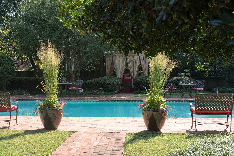 Imagen de piscina clásica de tamaño medio en patio trasero con adoquines de ladrillo