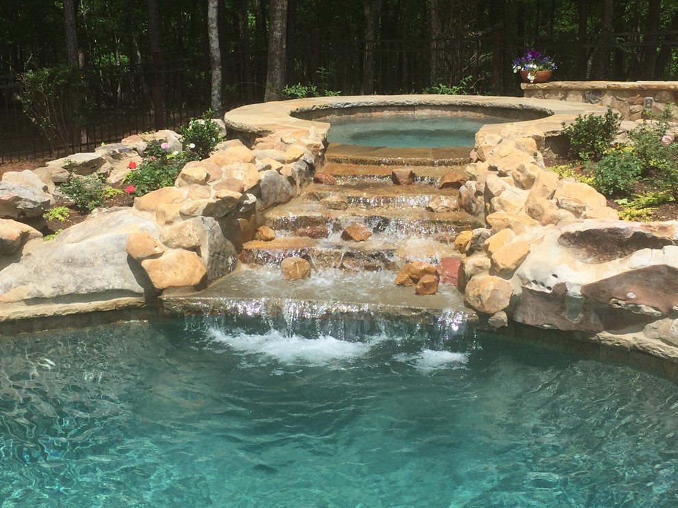 Esempio di una piscina naturale rustica personalizzata di medie dimensioni e dietro casa con una vasca idromassaggio e pavimentazioni in pietra naturale