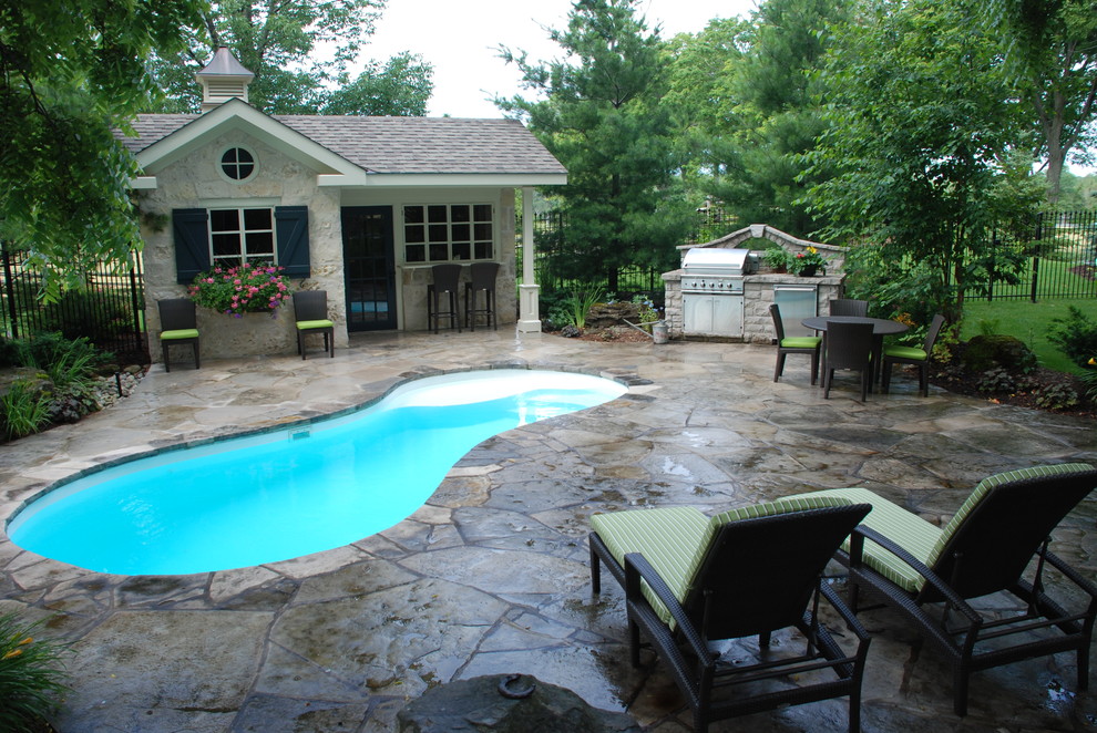 Example of a mid-sized classic backyard stone and kidney-shaped lap pool house design in Toronto