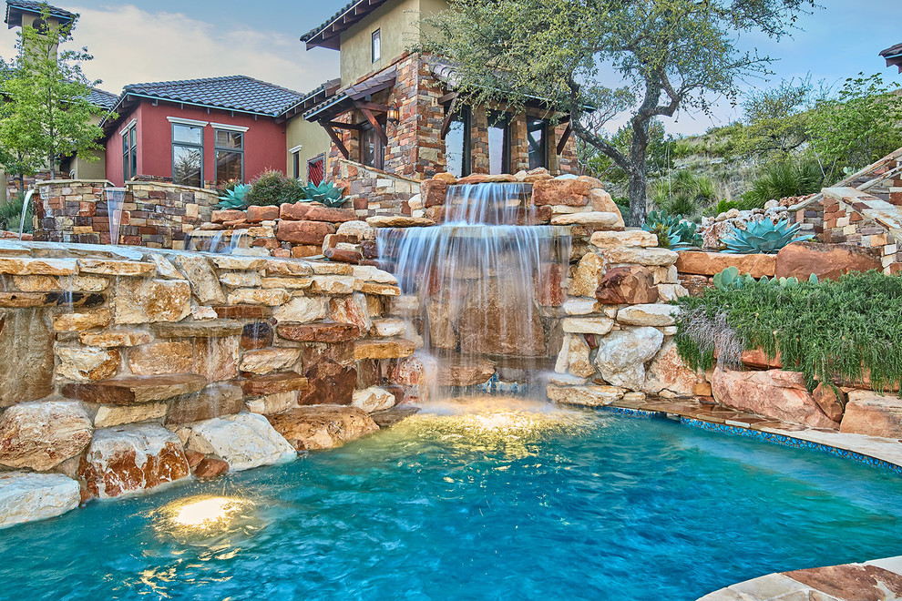 Ejemplo de piscina natural rural grande a medida en patio trasero con adoquines de piedra natural