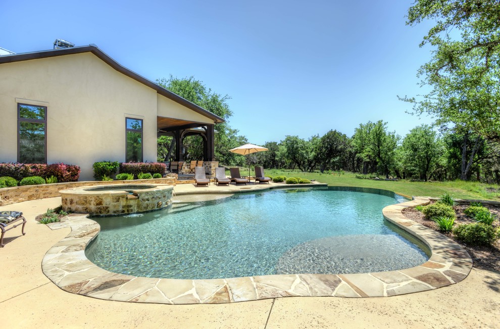 На фото: естественный бассейн среднего размера, произвольной формы на заднем дворе в стиле рустика с джакузи и покрытием из каменной брусчатки