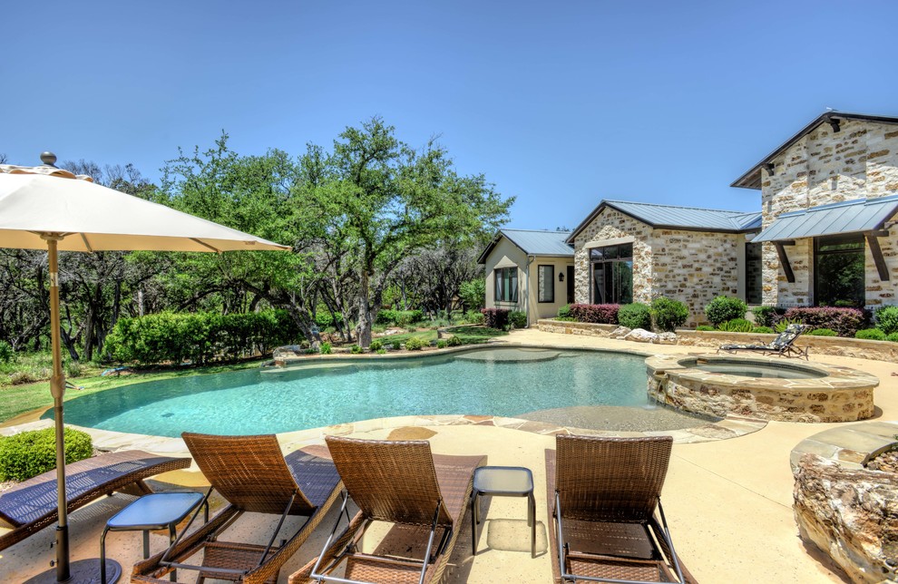 Ejemplo de piscina infinita rústica grande a medida en patio trasero con adoquines de piedra natural