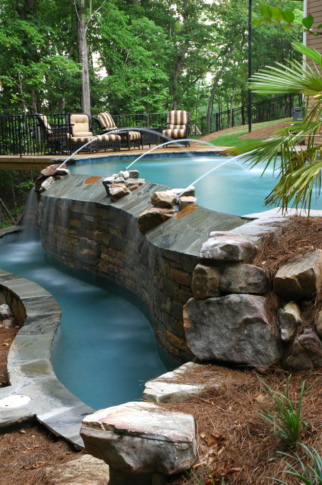 Immagine di una grande piscina a sfioro infinito rustica a "C" dietro casa con un acquascivolo