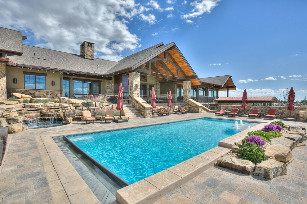 This is an example of an expansive rustic back rectangular natural swimming pool in Denver with stamped concrete.