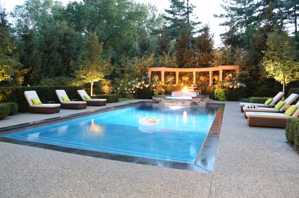 Klassischer Schwimmteich hinter dem Haus in rechteckiger Form mit Wasserspiel und Natursteinplatten in Toronto