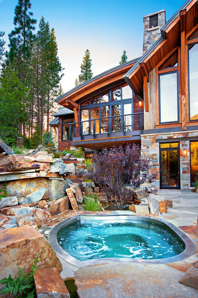 Esempio di una grande piscina stile rurale personalizzata dietro casa con una vasca idromassaggio e pavimentazioni in pietra naturale
