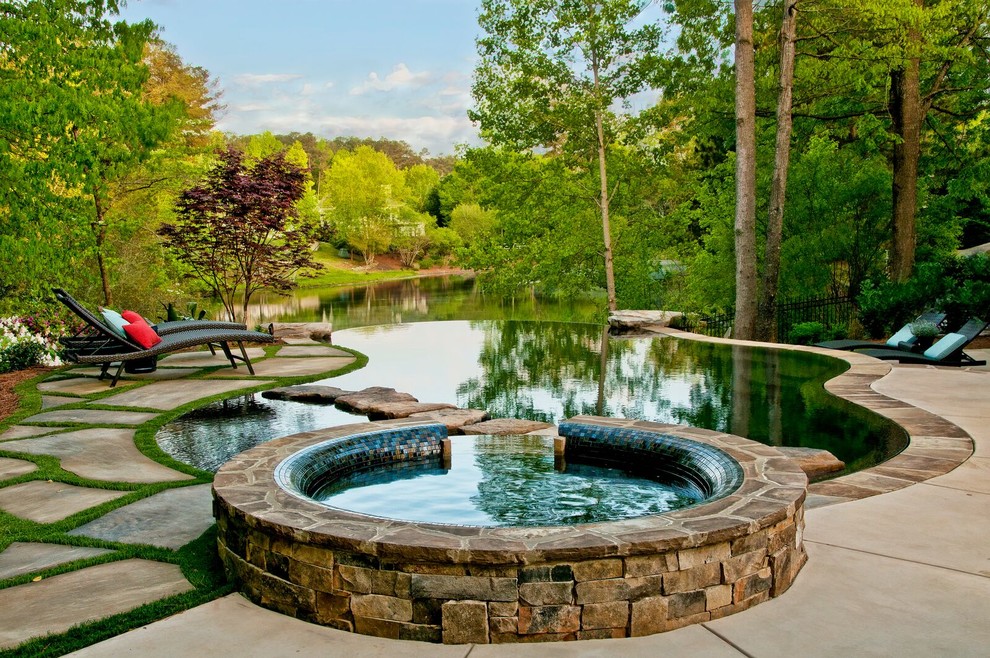 Immagine di una piscina a sfioro infinito rustica personalizzata con una vasca idromassaggio