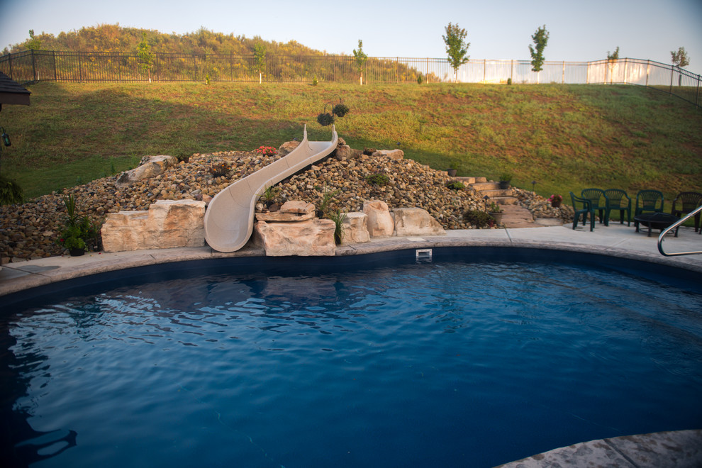 Стильный дизайн: естественный бассейн среднего размера, произвольной формы на заднем дворе в стиле рустика с водной горкой и покрытием из декоративного бетона - последний тренд