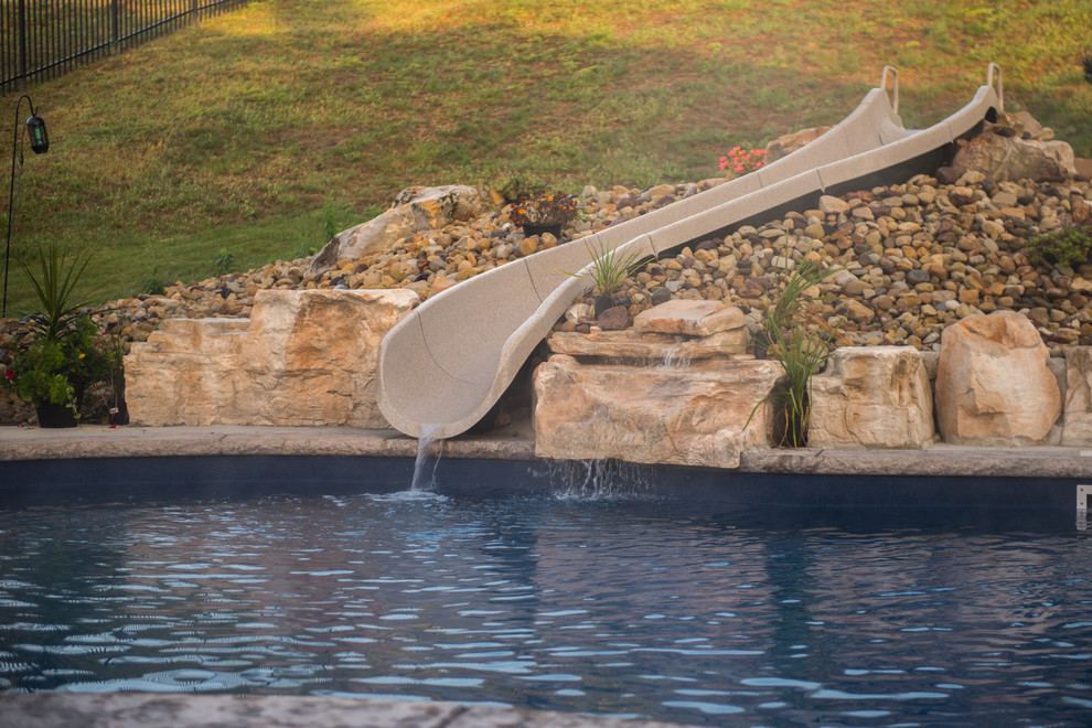 Immagine di una piscina naturale stile rurale personalizzata di medie dimensioni e dietro casa con un acquascivolo e cemento stampato