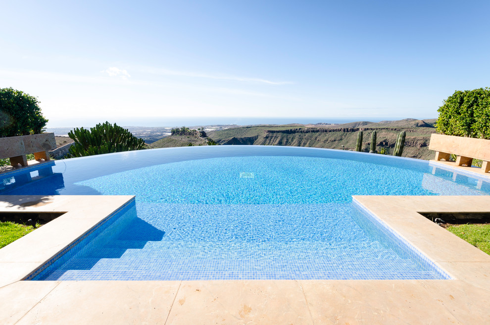 Photo of a large rustic back custom shaped infinity swimming pool in Other with natural stone paving and a shelter.