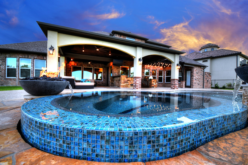 Immagine di una grande piscina monocorsia stile rurale personalizzata dietro casa con una vasca idromassaggio e pavimentazioni in pietra naturale