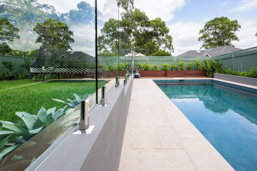 Ejemplo de piscina natural tradicional renovada grande rectangular en patio trasero con suelo de baldosas