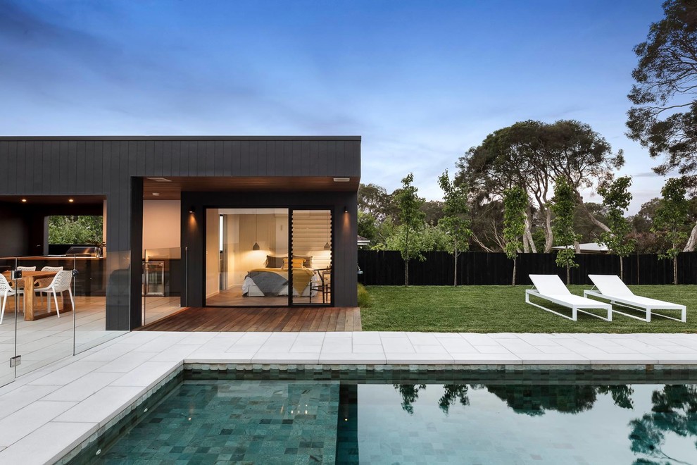 Immagine di una grande piscina monocorsia design rettangolare dietro casa con una dépendance a bordo piscina e piastrelle