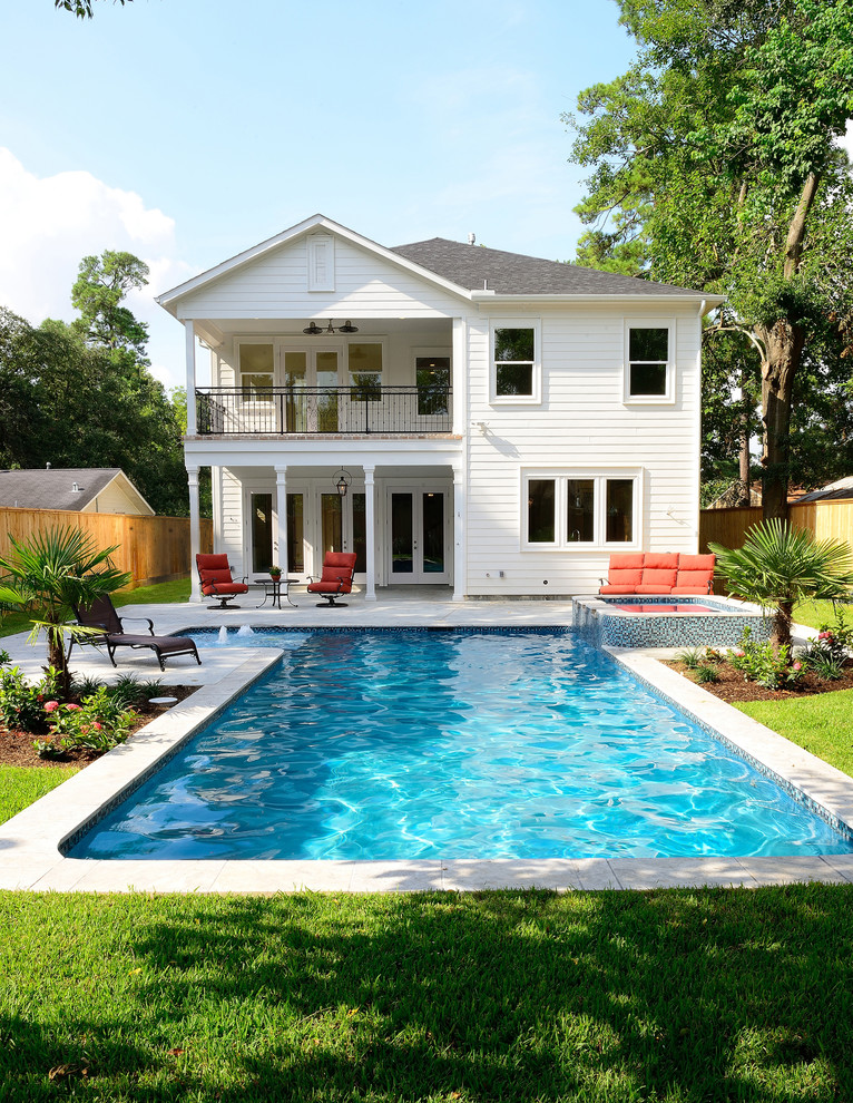 Immagine di una grande piscina monocorsia chic a "L" dietro casa con una vasca idromassaggio e lastre di cemento