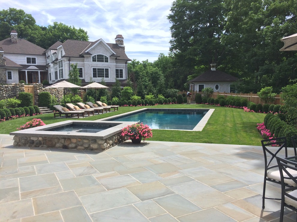 Cette image montre une piscine naturelle et latérale traditionnelle de taille moyenne et rectangle avec un bain bouillonnant et des pavés en pierre naturelle.