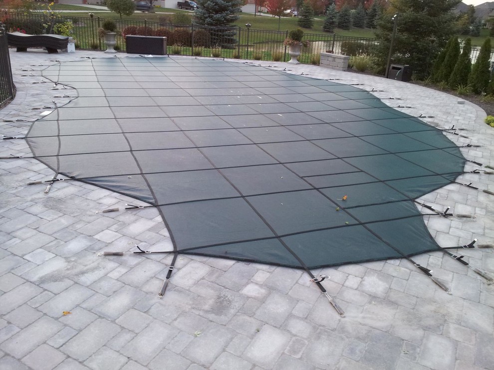 Esempio di una grande piscina naturale classica a "C" dietro casa con pavimentazioni in mattoni