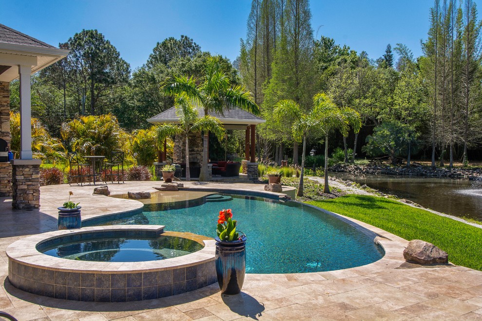 Ispirazione per una piscina a sfioro infinito tradizionale a "C" dietro casa con una vasca idromassaggio e pavimentazioni in pietra naturale