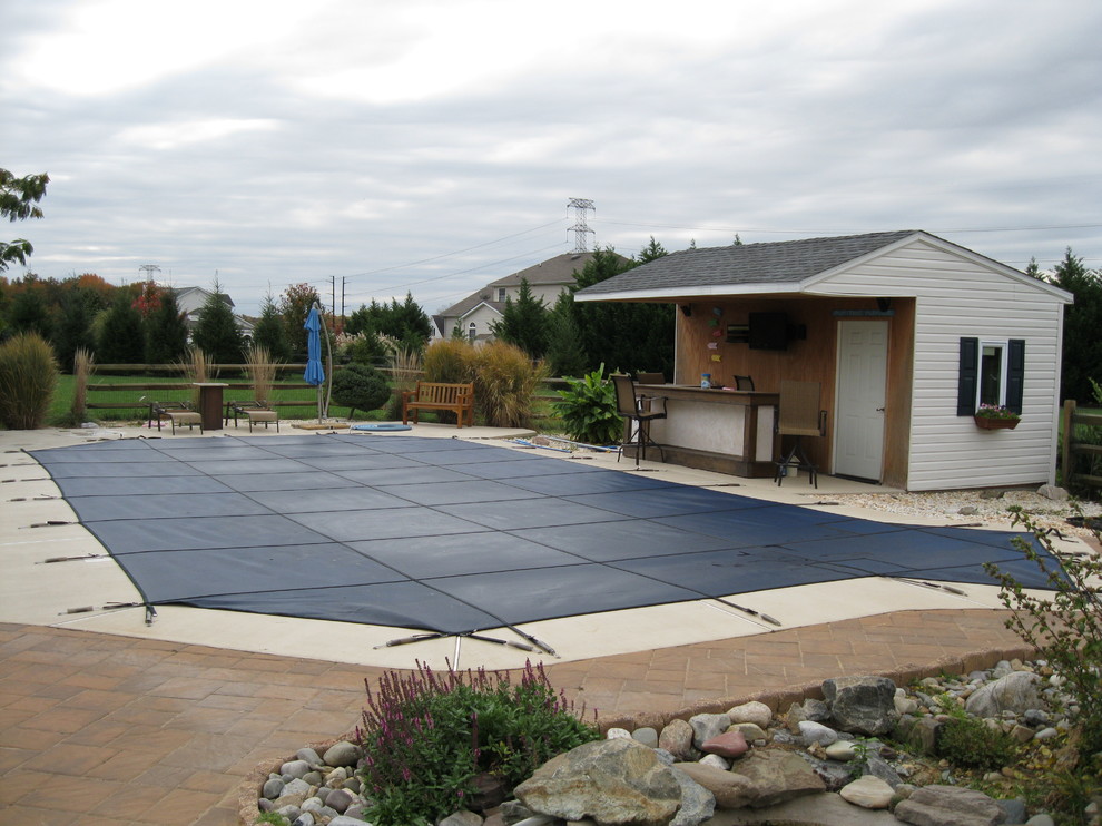 Foto de piscina natural tradicional de tamaño medio a medida en patio trasero con losas de hormigón