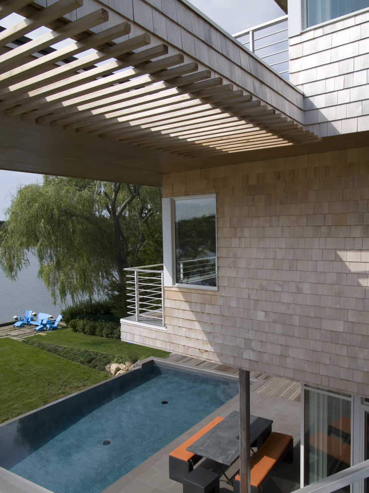 Example of a mid-sized minimalist backyard concrete paver and rectangular pool design in New York