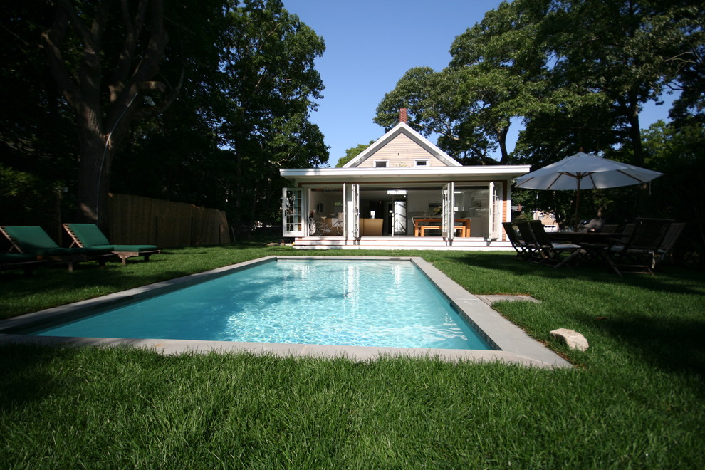 Ejemplo de piscina clásica rectangular en patio trasero con losas de hormigón
