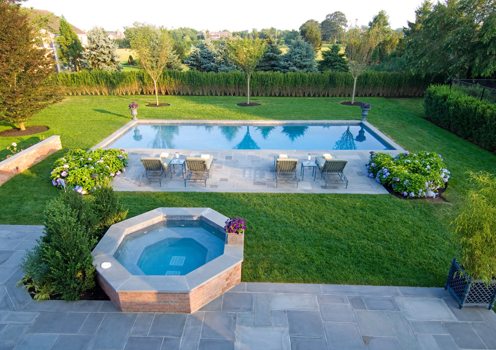 На фото: большой бассейн на заднем дворе в морском стиле с фонтаном и покрытием из каменной брусчатки с
