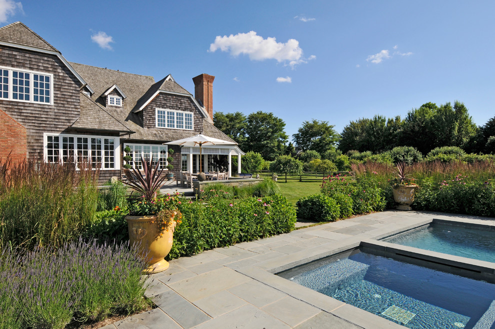 Idée de décoration pour une piscine arrière champêtre avec des pavés en pierre naturelle.