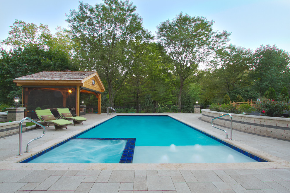 Foto de piscinas y jacuzzis alargados tradicionales de tamaño medio rectangulares en patio trasero con adoquines de piedra natural