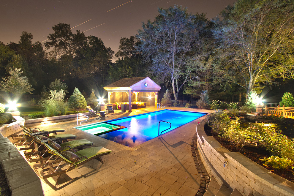 Immagine di una piscina monocorsia chic rettangolare di medie dimensioni e dietro casa con una vasca idromassaggio e pavimentazioni in pietra naturale
