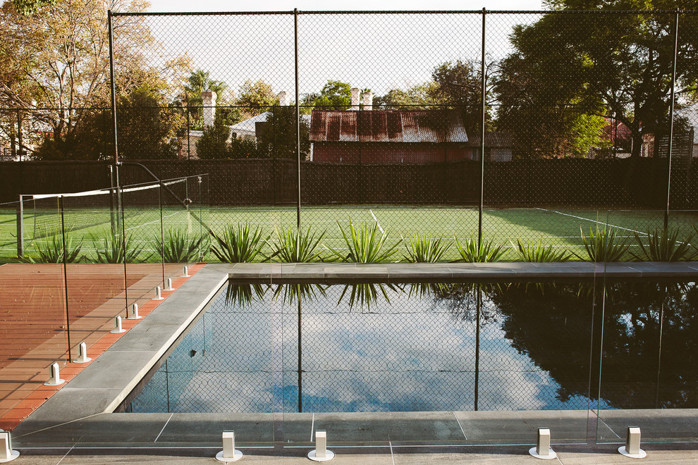 Modelo de casa de la piscina y piscina alargada contemporánea grande rectangular en patio trasero con adoquines de piedra natural