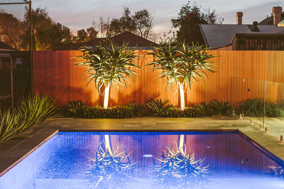 Diseño de casa de la piscina y piscina alargada actual grande rectangular en patio trasero con adoquines de piedra natural