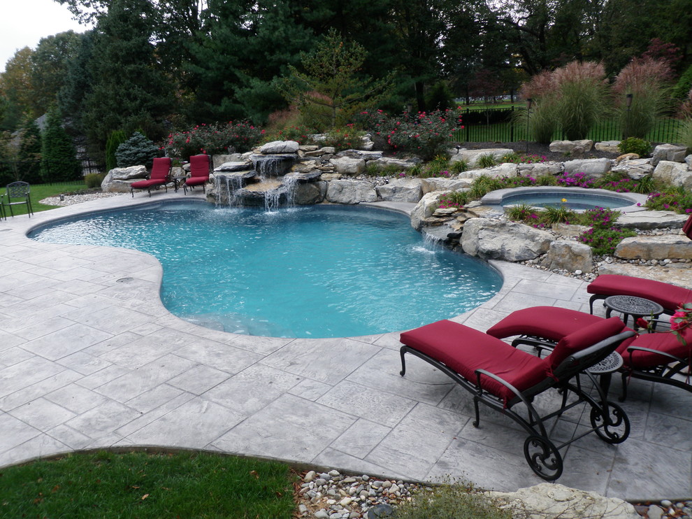 Elegant backyard stamped concrete and custom-shaped natural hot tub photo in Philadelphia
